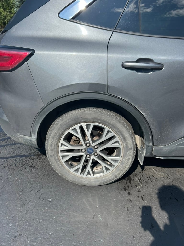 Silver SUV wheel with alloy rim on asphalt pavement, showing vehicle side profile